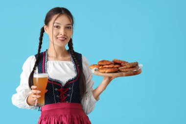 Güzel, genç, mutlu, Asyalı, Asyalı bir garson kız. Yanında abur cubur ve mavi arka planda bir bardak bira.