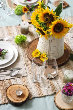 Güzel ayçiçekleri, çiçek dekoru ve mumlarla servis edilen yemek masası.