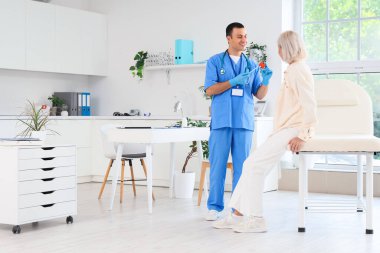 Erkek endokrinolojist klinikte kadın tiroit bezi modeli gösteriyor.