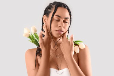 Hafif arka planda rastalı ve laleli genç Afro-Amerikalı kadın, yakın plan.