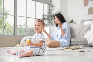 Küpleri olan şirin bir bebek ve yatak odasında çalışan bir anne.