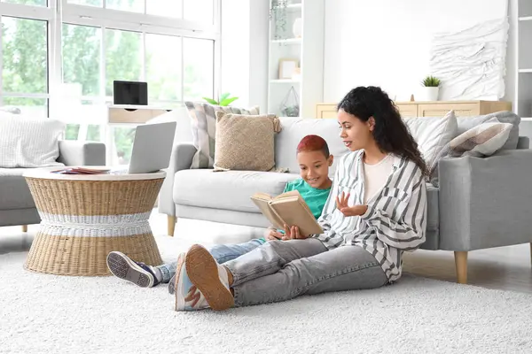 Annesi evde kitap okuyan küçük bir Afro-Amerikalı çocuk.