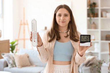 Dijital higrometresi ve evde termometresi olan genç bir kadın.
