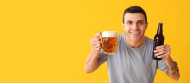 Sarı arka planda bira içen yakışıklı genç adam, mesaj için yer var.
