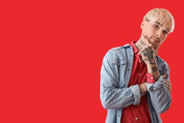 Kırmızı arka planda dövmeli genç adam.
