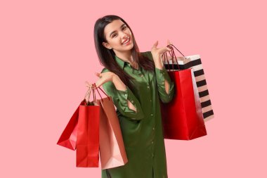 Alışveriş torbaları pembe bir arka plan üzerinde olan güzel kadın