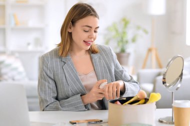 Makyaj vakfını evinde eline süren genç bir kadın.