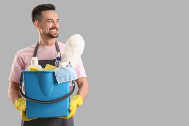 Gri arka planda temizlik malzemeleri olan erkek hademe.