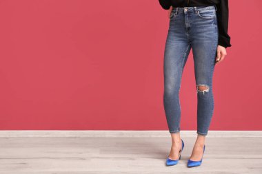 Kırmızı duvarın yanındaki şık kotlu genç kadın.