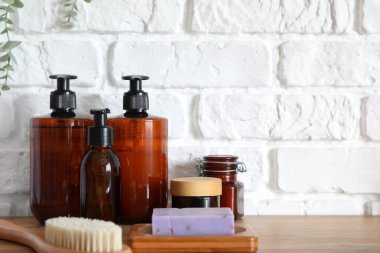 Masaj fırçalı banyo aksesuarları beyaz tuğla duvarın yanında.