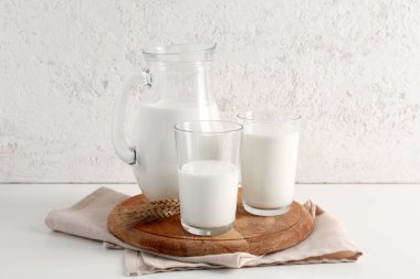 Sürahi ve beyaz arka planda taze sütle bardaklar