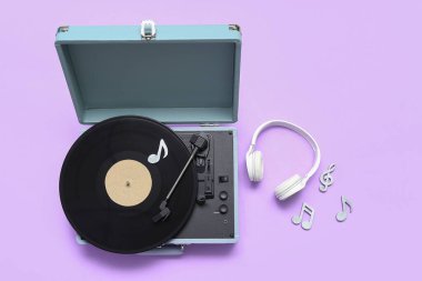 Vinil diski, kulaklığı ve eflatun arkaplanı üzerinde not tabelaları olan kayıt çalar