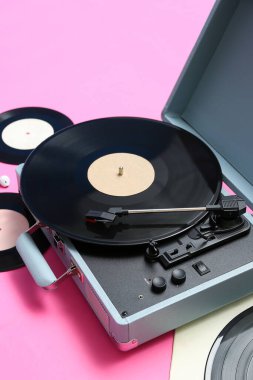 Pembe arka planda vinil diskleri olan kayıt çalar, yakın plan