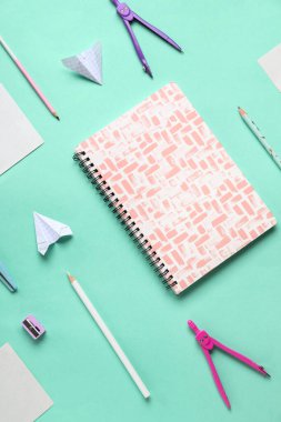 Kırtasiye malzemeleri ve turkuaz arka planda kağıt uçak kompozisyonu