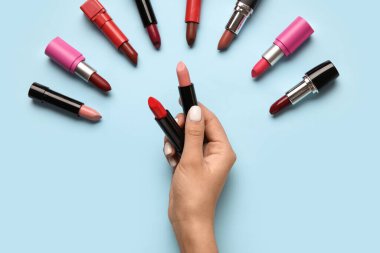 Mavi arka planda ruj tutan kadın.