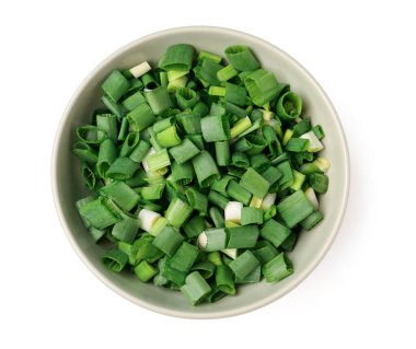 Beyaz arka planda taze kesilmiş yeşil soğanlı kase