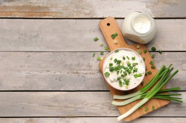 Hafif ahşap arka planda yeşil soğanlı bir kase lezzetli ekşi krema.