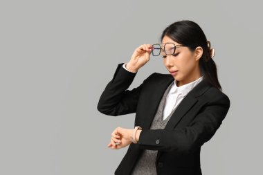 Genç Asyalı iş kadınının portresi gri arkaplanı kontrol ediyor