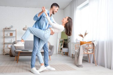 Mutlu genç çift evde dans ediyor.