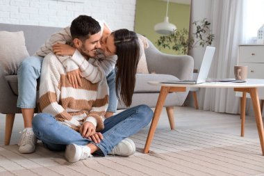 Evde sevgili erkek arkadaşına sarılan genç bir kadın.