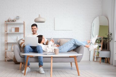 Evde dizüstü bilgisayarı ve cep telefonu olan mutlu bir çift.