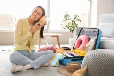 Güzel, genç bir kadın oturma odasında bavulunu toplarken kabuğunu dinliyor.