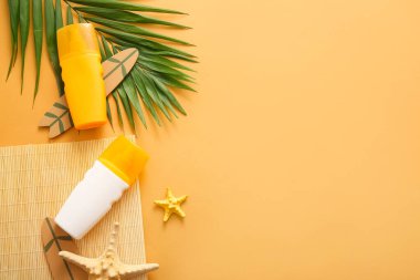 Güneş kremi şişeleri, deniz yıldızları, palmiye yaprakları ve turuncu arka planda sörf tahtası