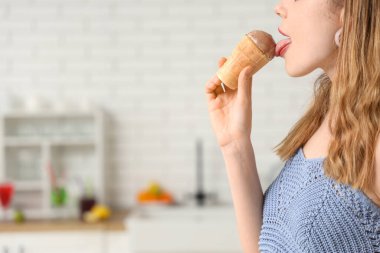 Evinde waffle bardağında çikolatalı dondurma yiyen genç bir kadın.