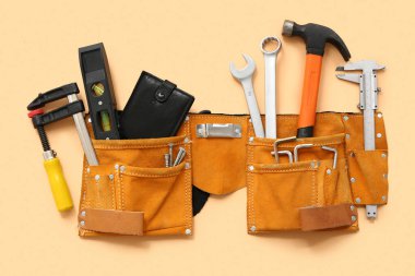 Bej arka planda farklı inşaat araçları ve cüzdanı olan kemer