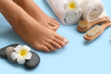 Mavi arka planda kaplıca pedikür yaptıran genç bir kadın.