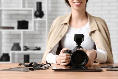 Profesyonel fotoğraf makinesi olan kadın fotoğrafçı ve ahşap masada oturan modern aletler.
