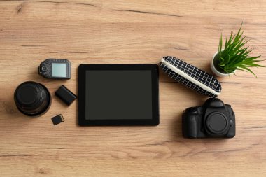 Tablet bilgisayarlı kompozisyon ve ahşap arka planda profesyonel fotoğrafçı ekipmanı.