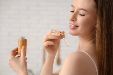 Omuzlarına kozmetik yağı süren güzel genç bir kadın.