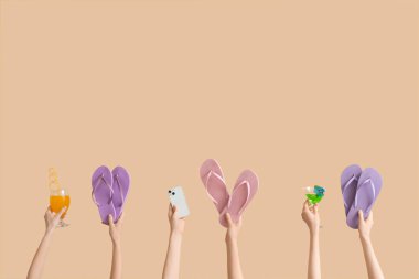 El ele tutuşan üç çift parmak arası terlik kokteyl ve bej arka planda cep telefonu.