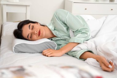 Pijamalı genç bir kadın evdeki rahat ortopedik yastıkta uyuyor.