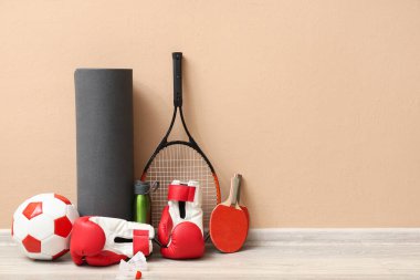 Bej duvarın yanında farklı spor aletleri var.