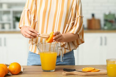 Mutfakta meyve suyu hazırlamak için portakal sıkan güzel bir kadın.