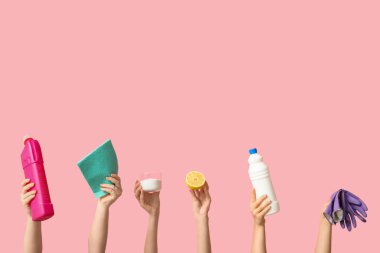Pembe arka planda kadın eli bez, deterjan şişeleri, limon, kavanoz temizlik maddesi ve lastik eldivenler.
