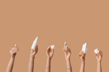 Şişeli kadın elleri ve bej arka planda kozmetik ürünleri kavanozları