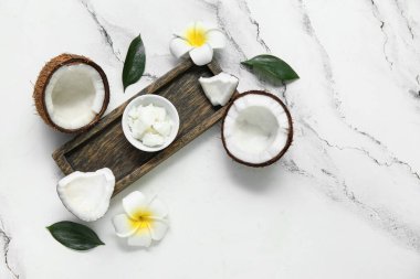 Ahşap tepsi, çiçekler ve mermer arka planda doğal hindistan cevizi yağlı kase.