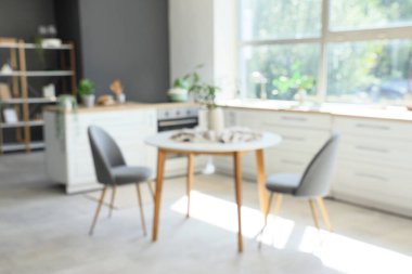 Mutfağın içi tezgahlı, yemek masası bitkili, bulanık manzaralı.