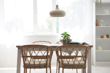 Odanın içinde ahşap masa, sandalyeler ve asılı lamba var.