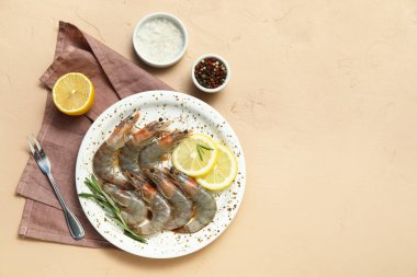 Taze çiğ karidesli tabak, bej arka planda limon ve biberiye
