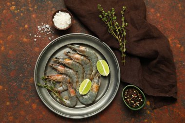 Koyu arkaplanda taze çiğ karides ve limon tabağı.