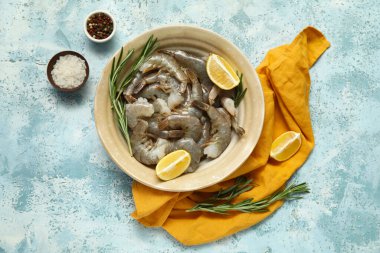 Mavi arka planda taze çiğ karides, limon ve biberiye.