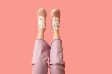 Pembe arka planda şık spor ayakkabılı genç kadın bacakları.