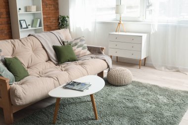 Rahat bir kanepe, puf, sehpa ve oturma odasının içindeki çekmeceler.