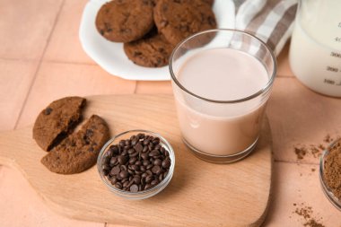 Bir bardak tatlı çikolatalı süt ve bej kaplamalı lezzetli kurabiyeler.
