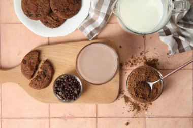 Lezzetli kurabiyeli bir bardak çikolata sütü ve bej fayanslı kakao tozu.