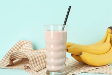 Bir bardak çikolatalı süt ve mavi arka planda taze muzlar.